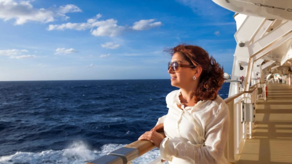 A clear sky and endless ocean frame a woman enjoying her cruise, emphasizing the serene and memorable voyages that result from diligent ocean cruise planning with Dorian Destinations.