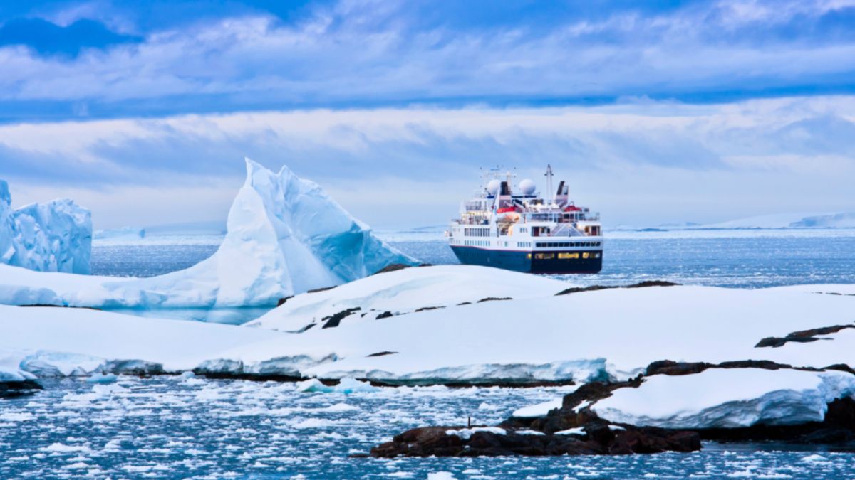 A cruise ship navigates through icy waters, surrounded by towering icebergs during an Antarctic expedition.