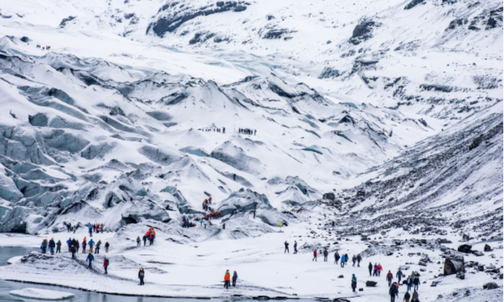 Expedition travelers navigate a snowy mountainside near a glacier in the Himalayas, surrounded by stunning alpine scenery.