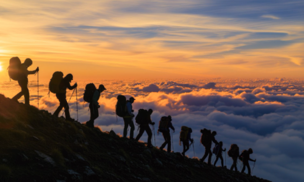 A group of hikers stands atop a mountain, silhouetted against a vibrant sunset, showcasing the spirit of expedition travel destination.