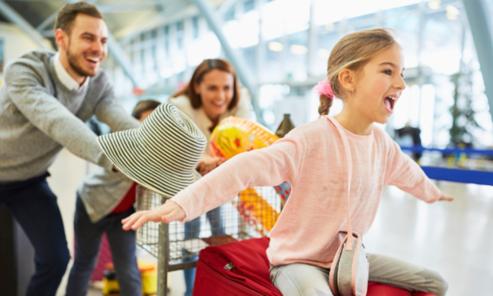 A family stands at the airport with luggage, preparing for their group travel adventure.
