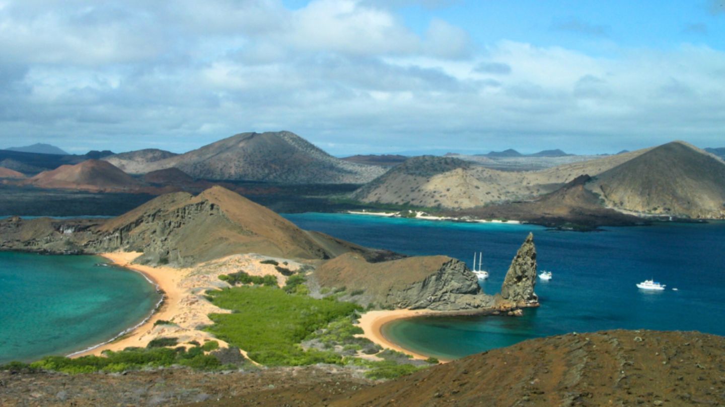 A cloudy blue sky stretches over the Galápagos Islands, creating a moody atmosphere.