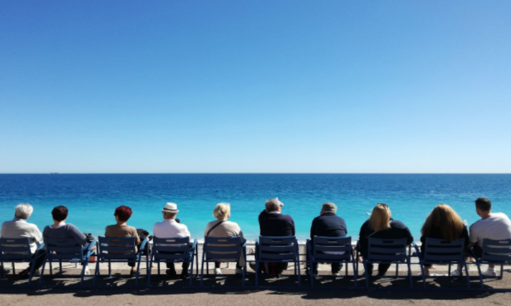 Corporate Event Retreats Go Global: International Planning Made Simple 3 Attendees of an international corporate event retreat relax on chairs near the ocean, surrounded by a beautiful coastal landscape.