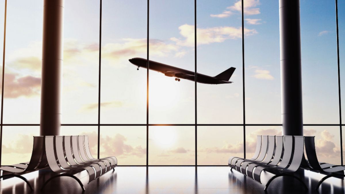 An airplane in flight viewed through an airport window, symbolizing luxury air travel.