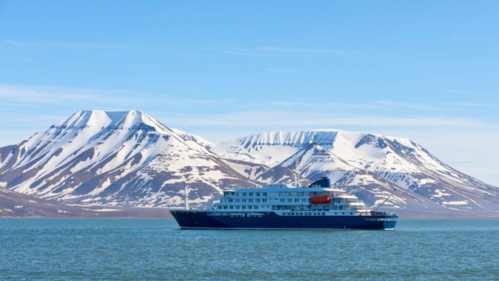 Antarctica Expedition Luxury Options: Premium Ships and Exclusive Experiences 1 A cruise ship sails in icy waters near towering mountains during an Antarctica expedition.