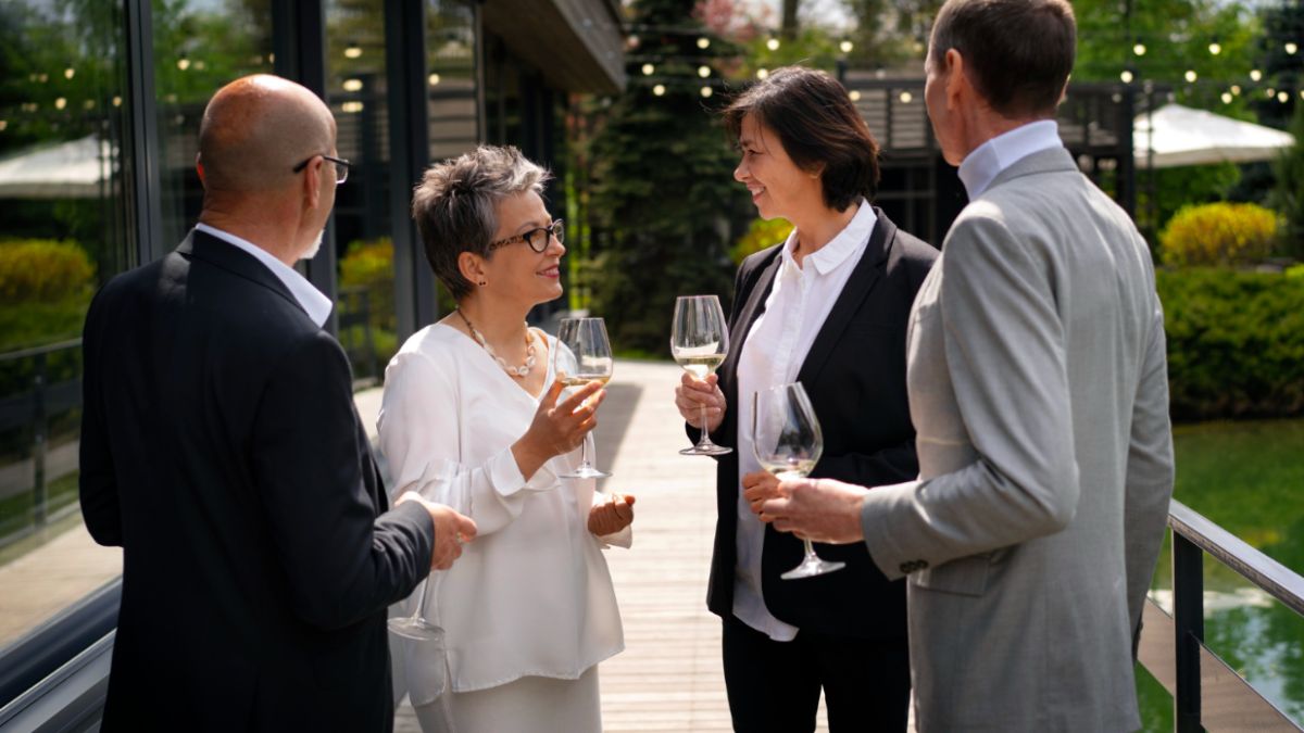 Four colleagues discussing ideas and sipping wine during a corporate event retreat.