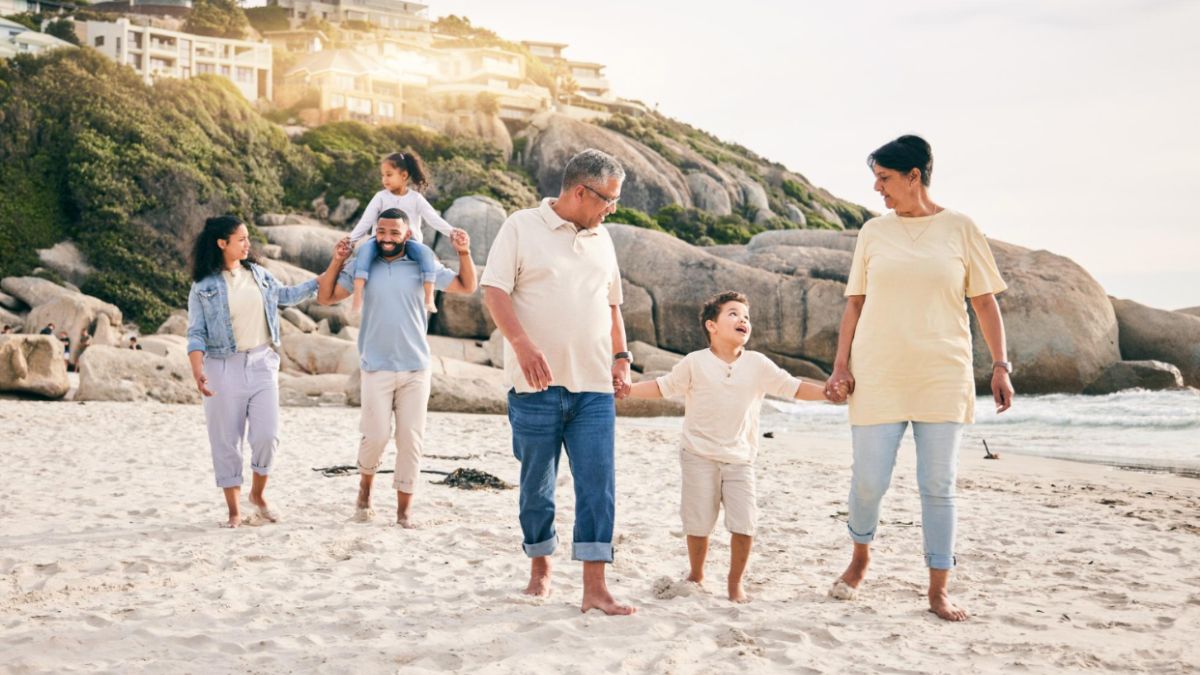 A family walks on the beach with their kids, surrounded by sand and sea, enjoying quality time together as a result of group and family travel planning.