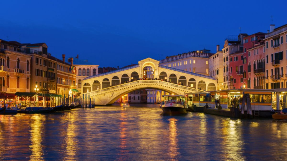 A picturesque bridge spans a serene canal in Venice, showcasing Italy’s cultural luxury and architectural beauty.