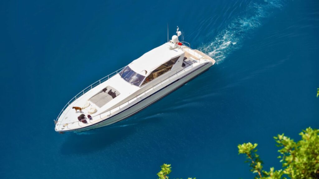 Italy Cultural Luxury: Private Yacht Charters Along the Amalfi Coast and Vintage Car Tours Through Tuscany 1 A white yacht glides across the calm blue waters of the Amalfi Coast, with cliffs and colorful villages in the background.