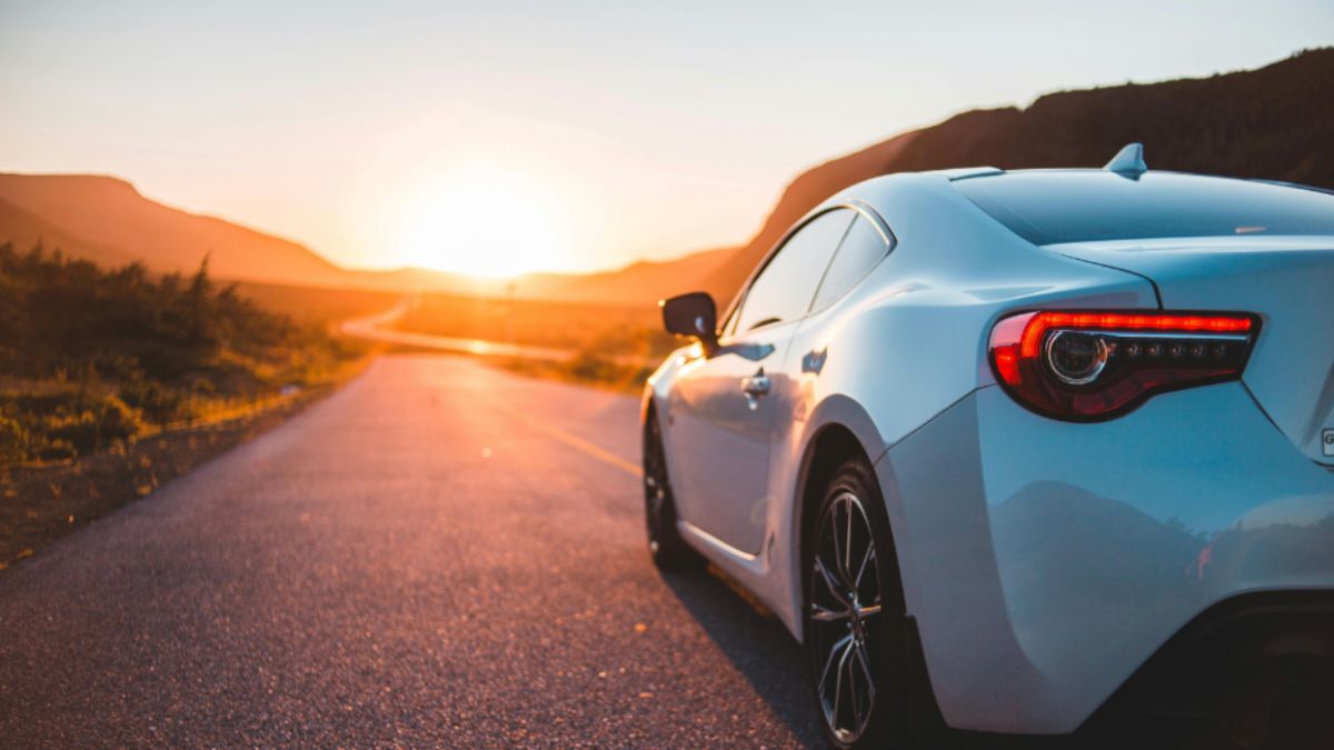 Italy Cultural Luxury: Private Yacht Charters Along the Amalfi Coast and Vintage Car Tours Through Tuscany 3 A white sports car speeds down a picturesque Italian road at sunset, showcasing a blend of luxury and cultural beauty.