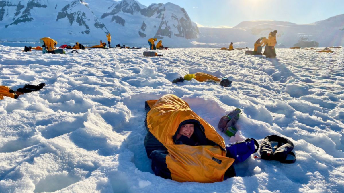 Travelers relax on the snow during Antarctica expedition itineraries, highlighting the joy of polar exploration.