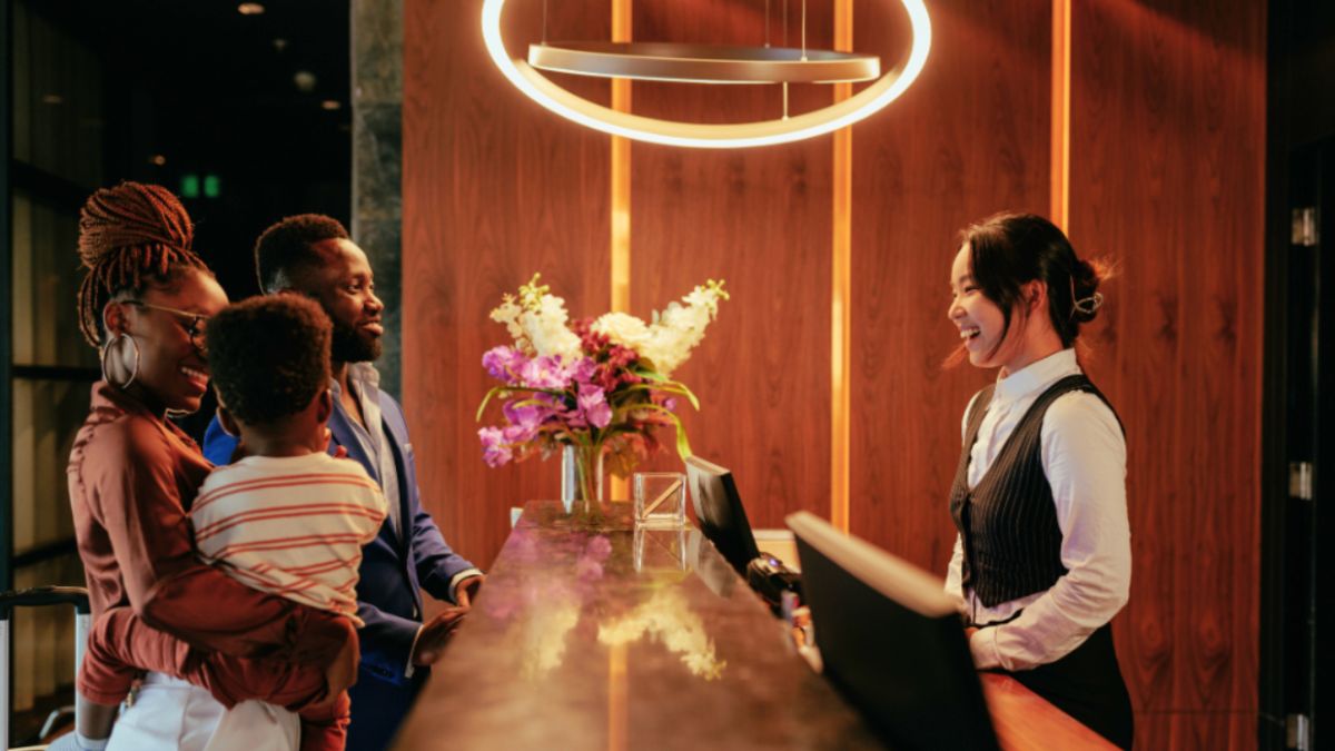 A family checks in at a hotel front desk, showcasing a luxury travel planning experience.