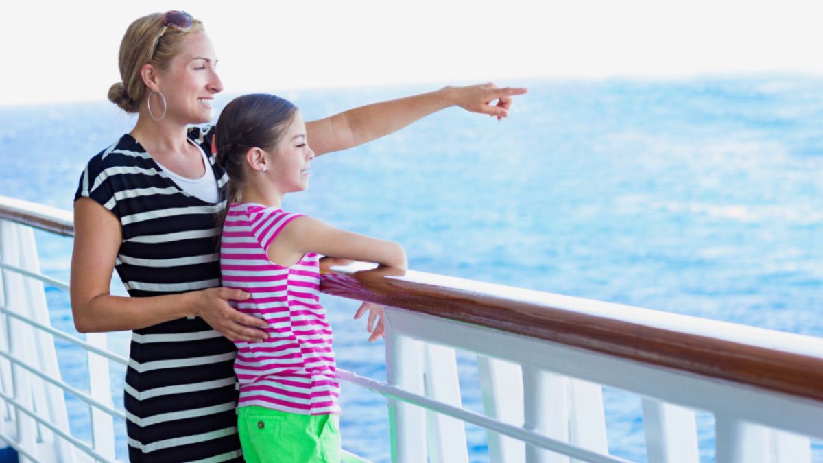 A woman and a child on a cruise ship, looking out at the ocean together.