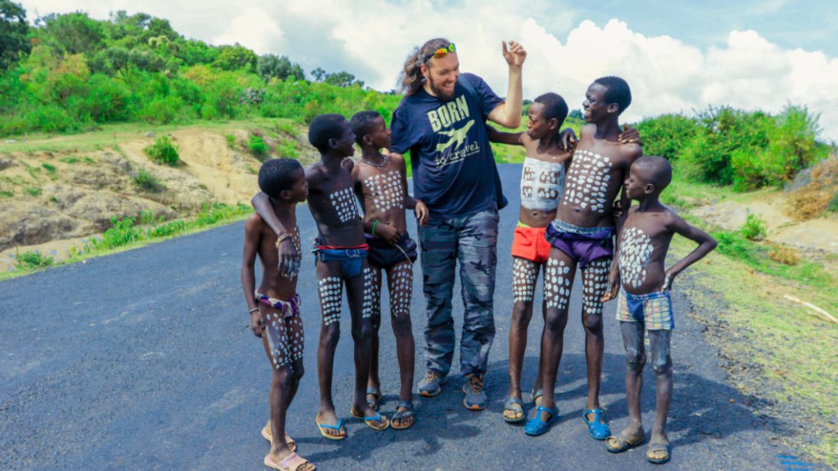 A tourist engaging with children from a local African community during an African safari cultural encounter.