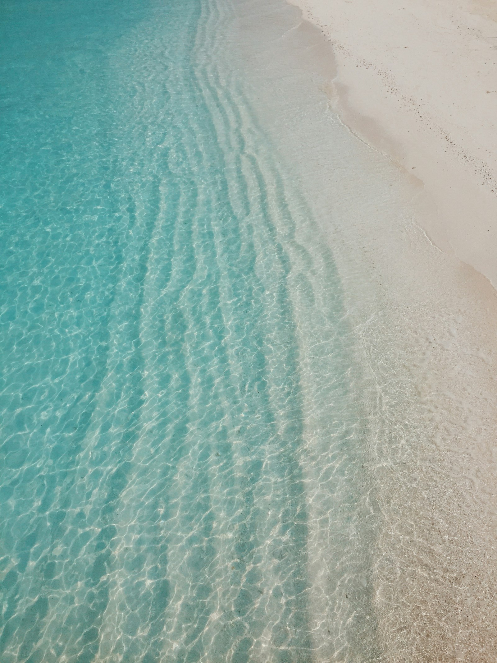Clear shallow turquoise water lapping a quiet empty shoreline