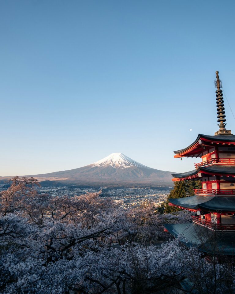The best time to visit Japan for cherry blossoms: Chureito Pagoda framed by pink sakura with snow-capped Mount Fuji behind it.