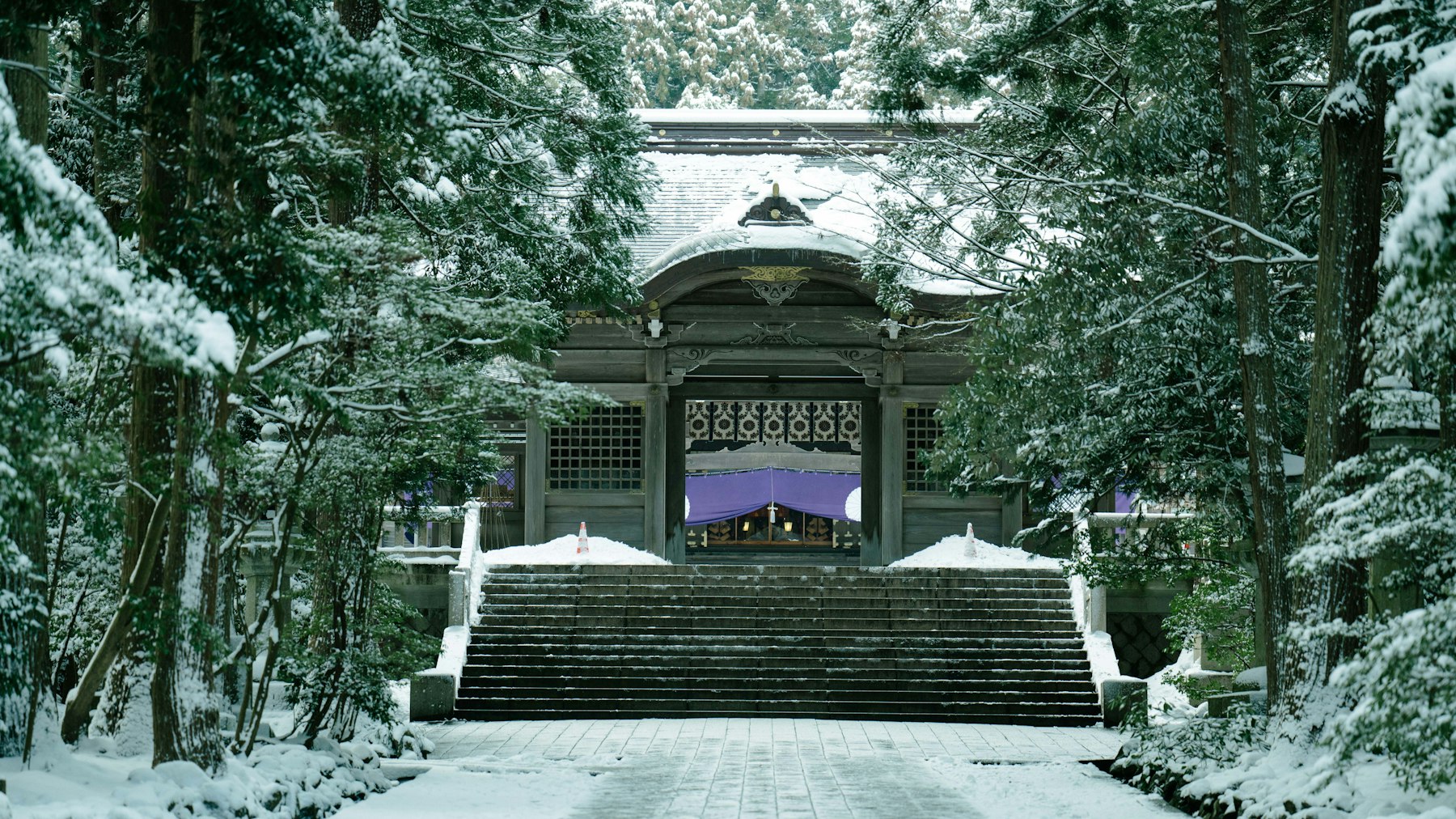 Winter is the quietest best time to visit Japan: a snow-covered stone walkway leads to a traditional building under fresh powder.