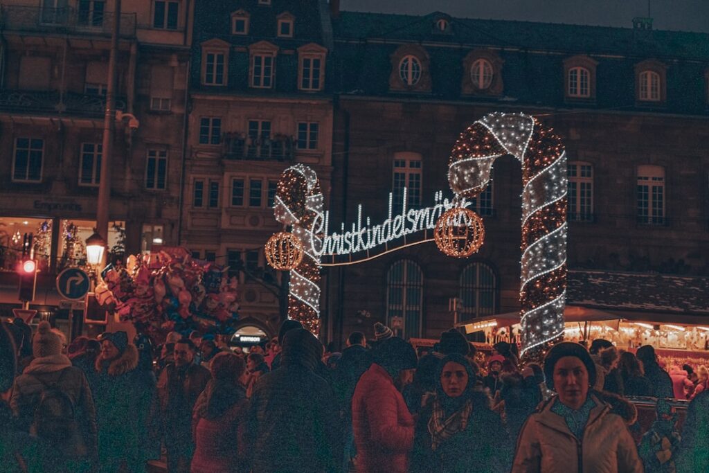 Crowd of visitors walking through the Strasbourg Christmas market past half-timbered buildings