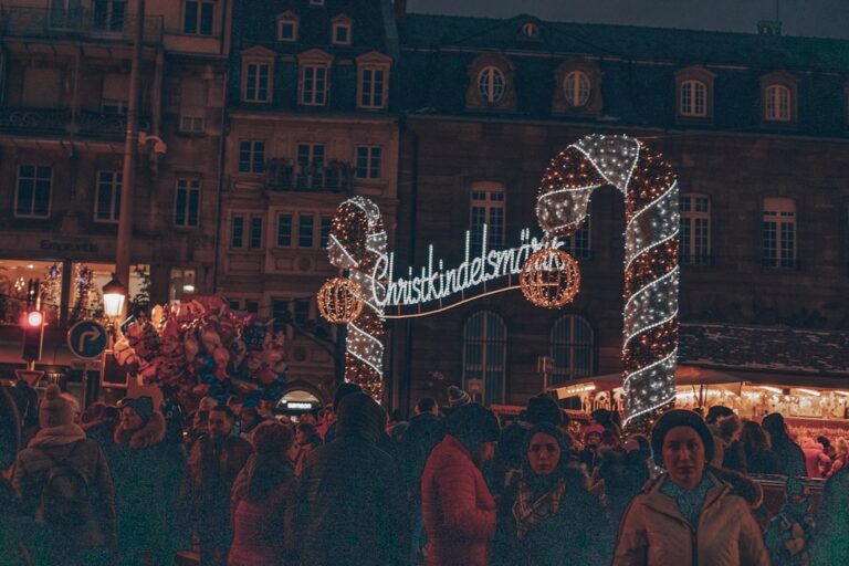 Crowd of visitors walking through the Strasbourg Christmas market past half-timbered buildings