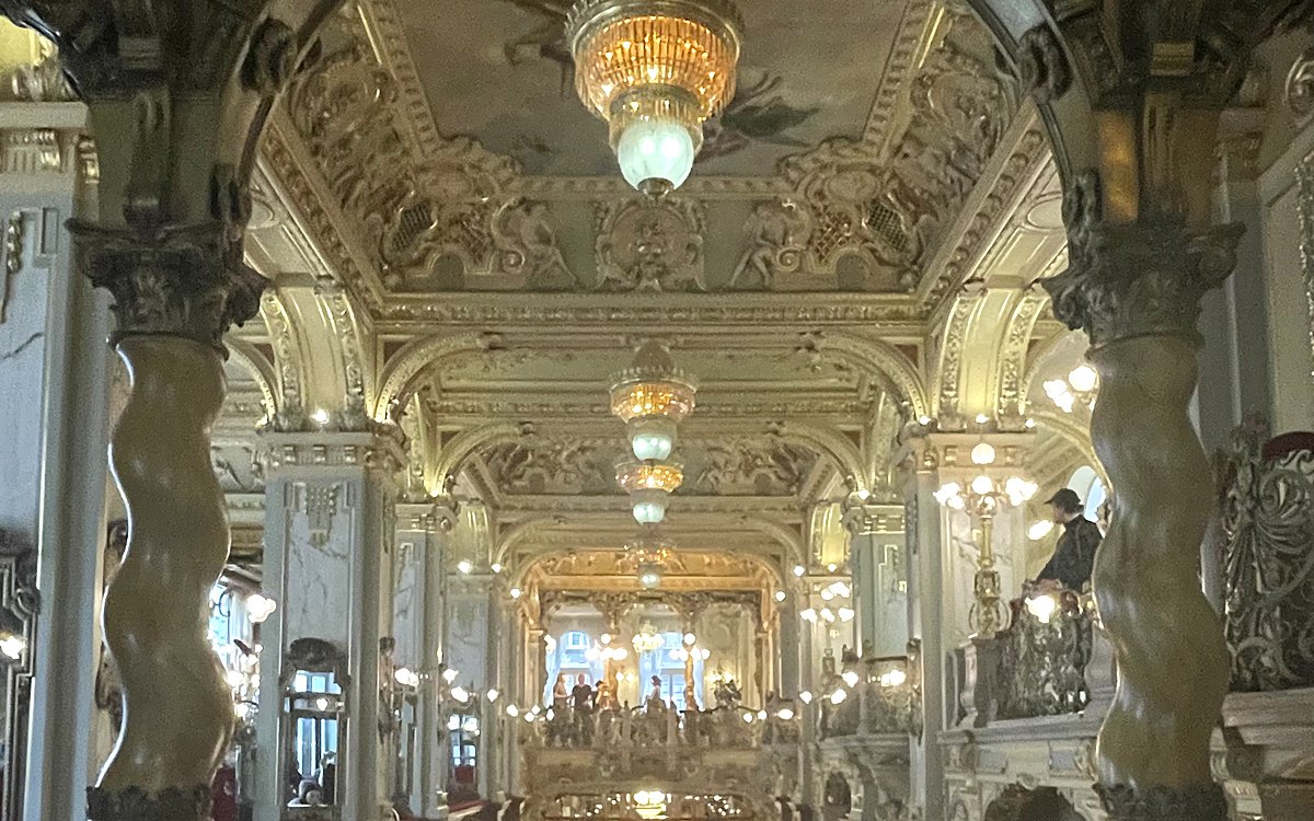 Gilded interior of the New York Cafe in Budapest, with chandeliers and a painted ceiling