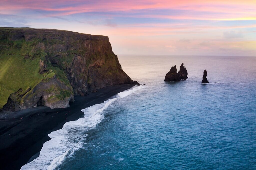 Mountain cliff rising from the Iceland coastline during daytime