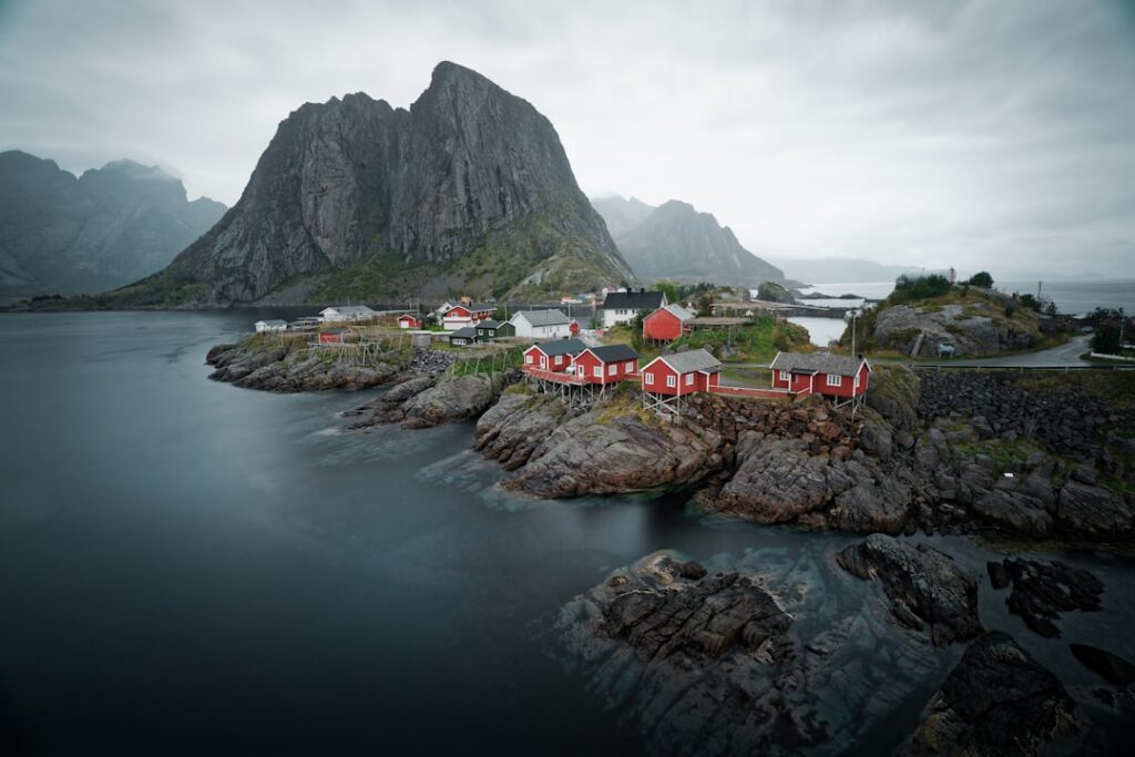 Red and black rorbu fishing houses beside a fjord in Norway's Lofoten Islands