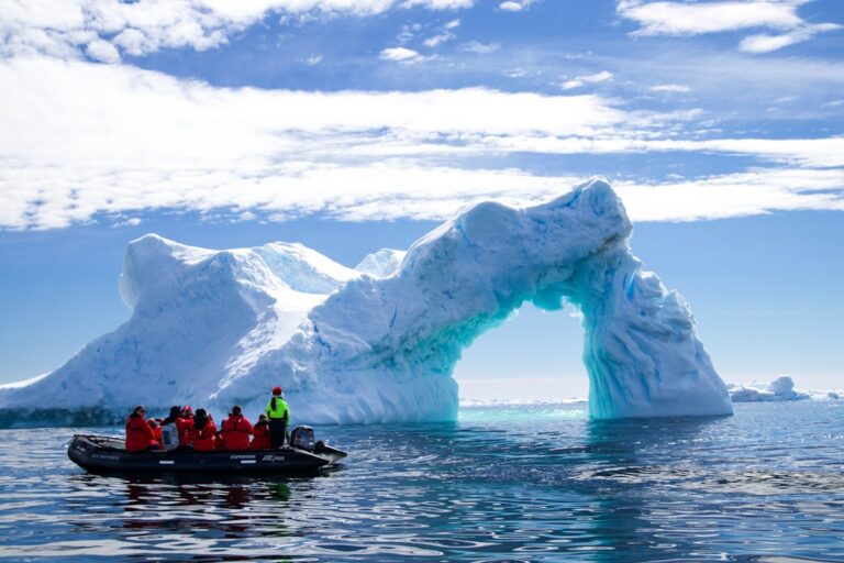 Zodiac expedition boat with travelers approaching an Antarctic iceberg
