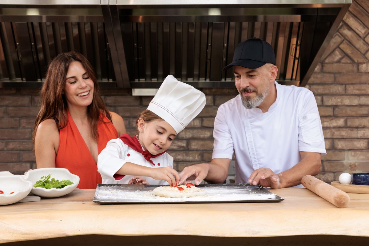 Family and resort chef making pizza together during a hands-on culinary experience
