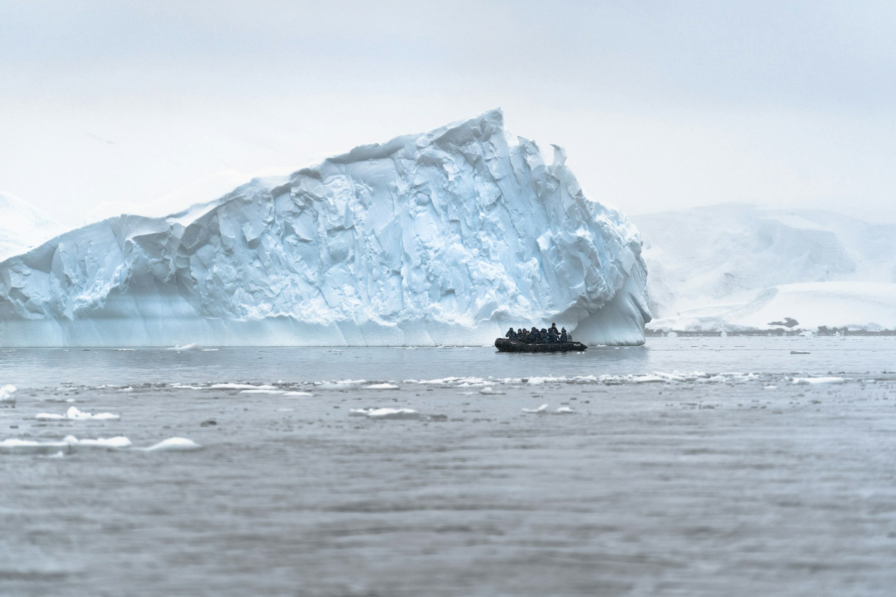 A small boat dwarfed by icebergs on an Antarctica expedition cruise