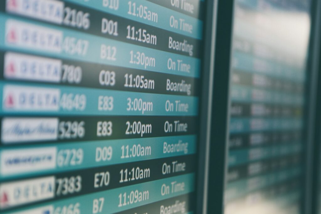 An airport departures board showing flight times, the screen travellers watch while wondering about the best day to book flights.