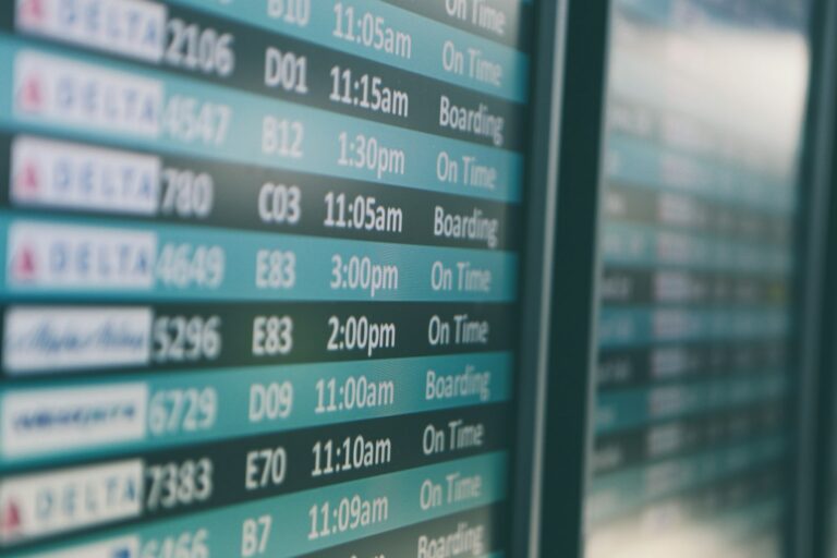 An airport departures board showing flight times, the screen travellers watch while wondering about the best day to book flights.