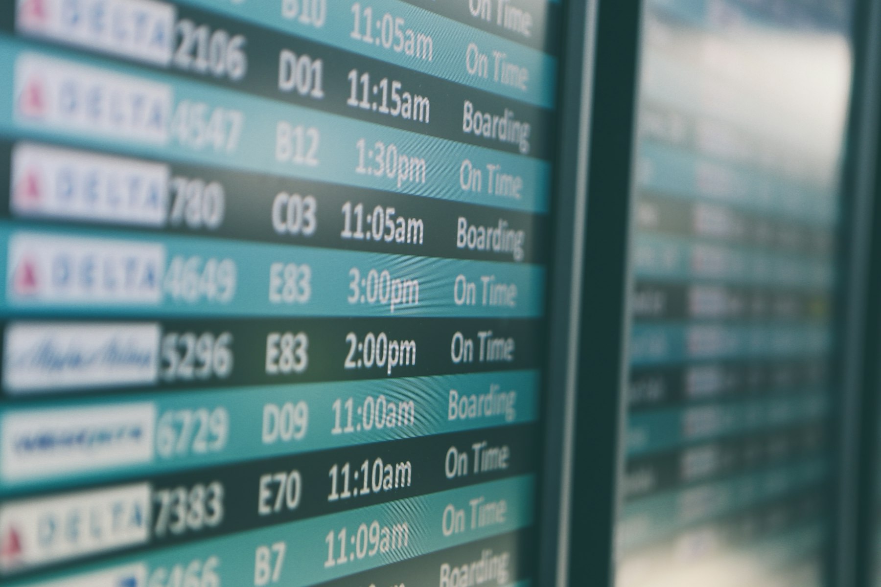 An airport departures board showing flight times, the screen travellers watch while wondering about the best day to book flights.