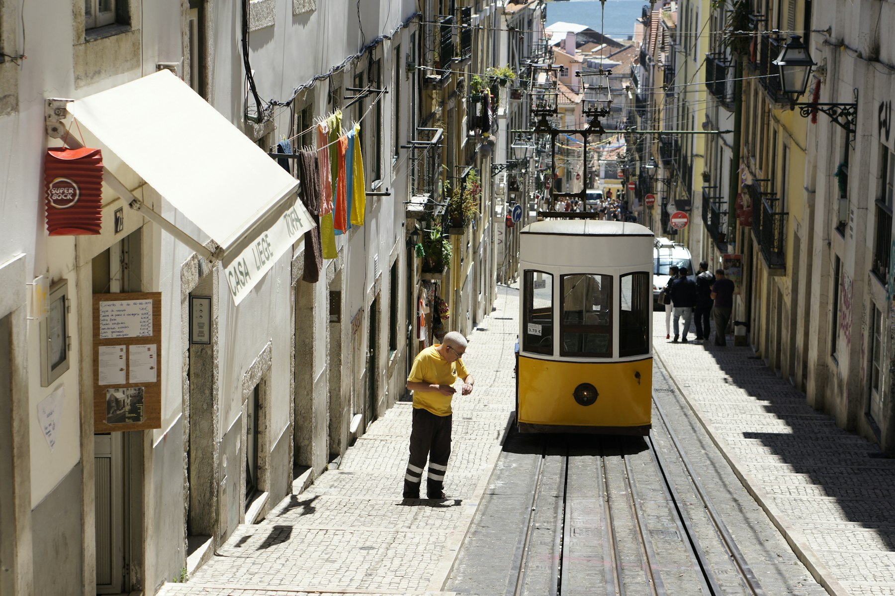 Lisbon is one of the best girls trip destinations for city lovers: a yellow tram climbing a steep tiled street.