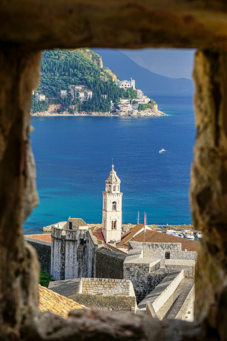 The stone bell tower and city walls of Dubrovnik above the blue Adriatic, one of the best places to visit in Europe if you go in May rather than August