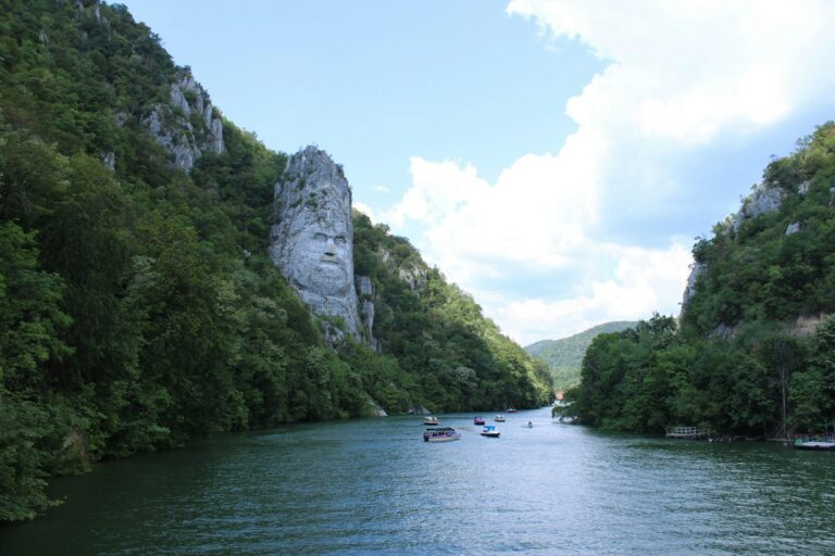 Small boats on the Danube between steep wooded cliffs in Romania, on the downstream half of the Europe Danube River that most cruises never reach.