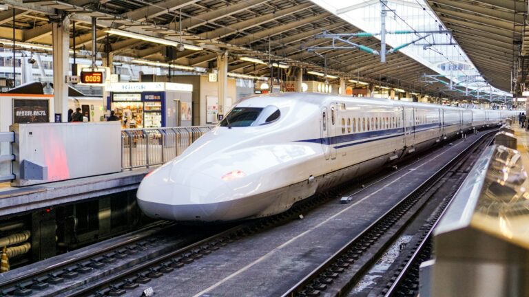 A white Shinkansen bullet train arriving at a platform, the spine of any 10 day Japan itinerary