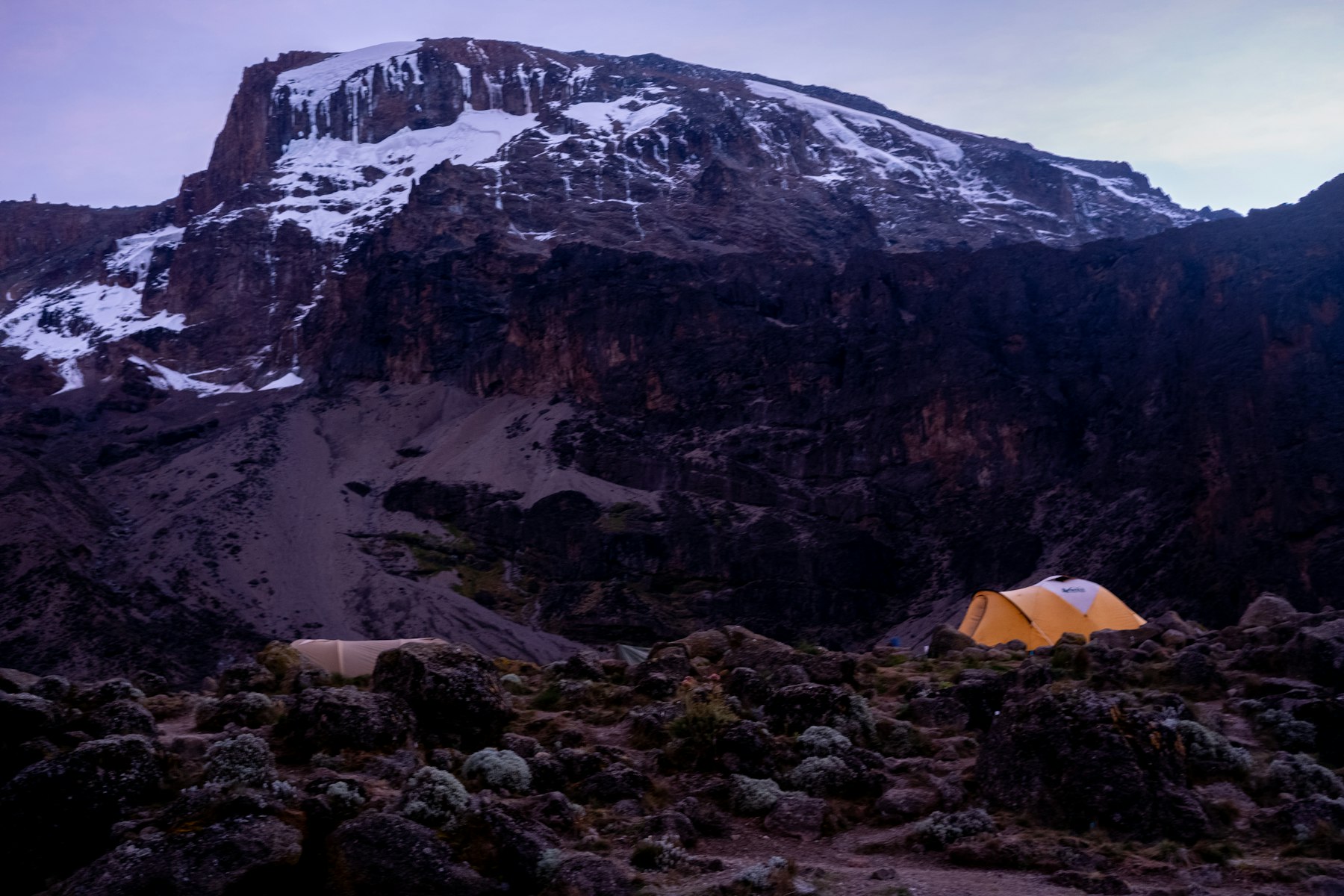 A tent pitched on bare rock below the snow line on Mount Kilimanjaro, the kind of high camp Kilimanjaro climb tours use before a summit night