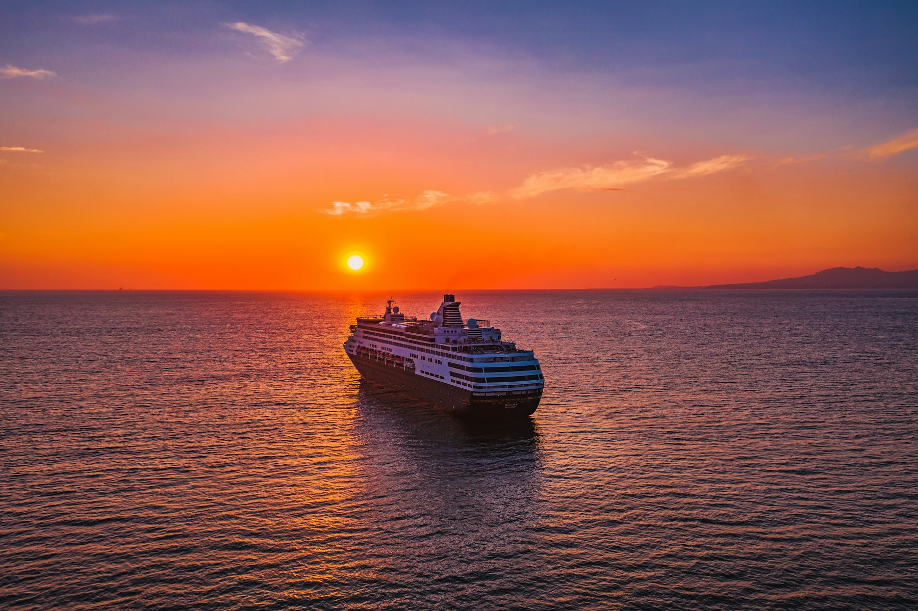 A cruise ship at sea at sunset, the kind of sailing the best luxury cruise lines build their itineraries around.