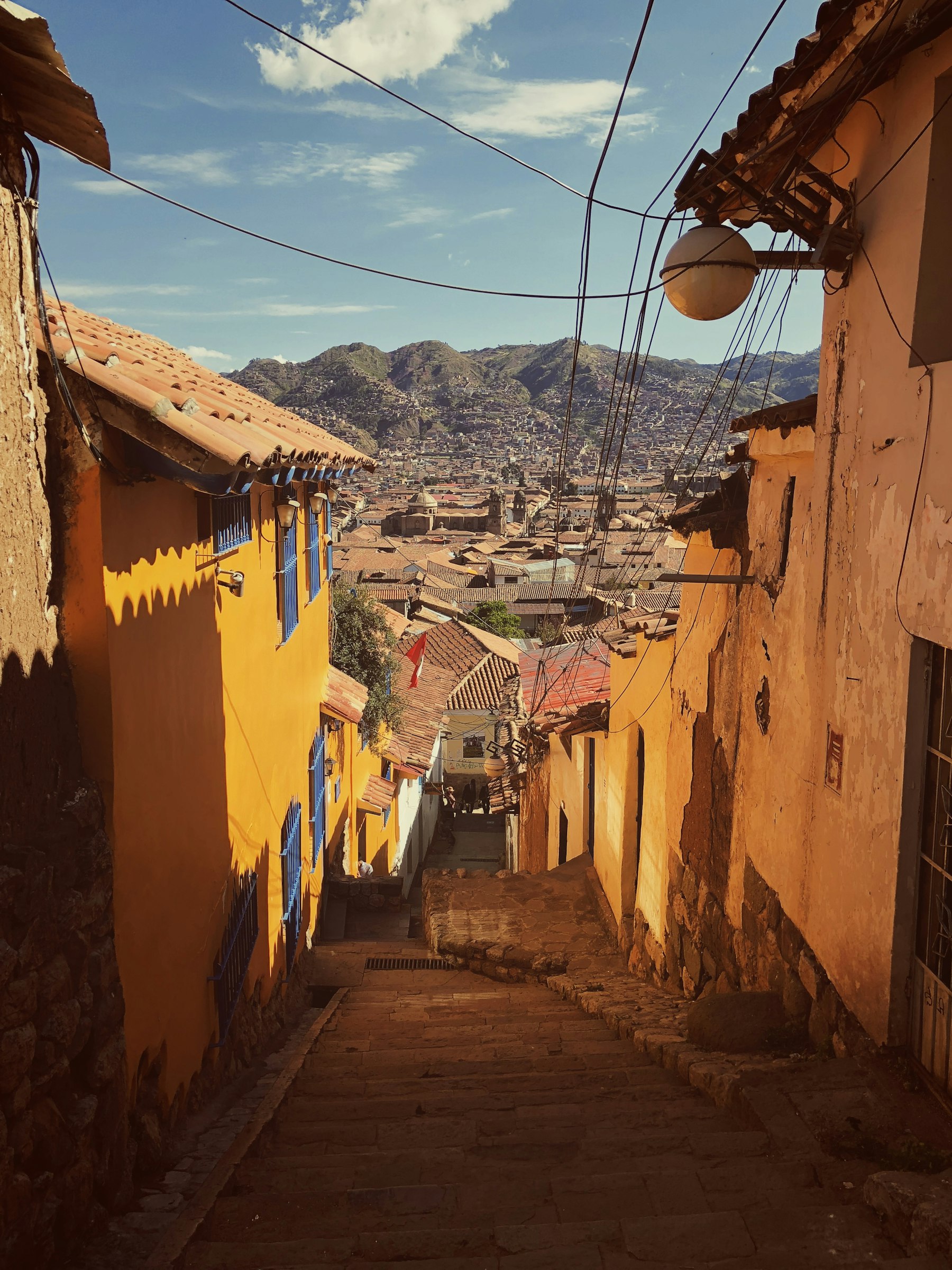 Orange-roofed houses climbing a green hillside in Cusco, the 3,400-metre city that belongs at the end of a Peru itinerary