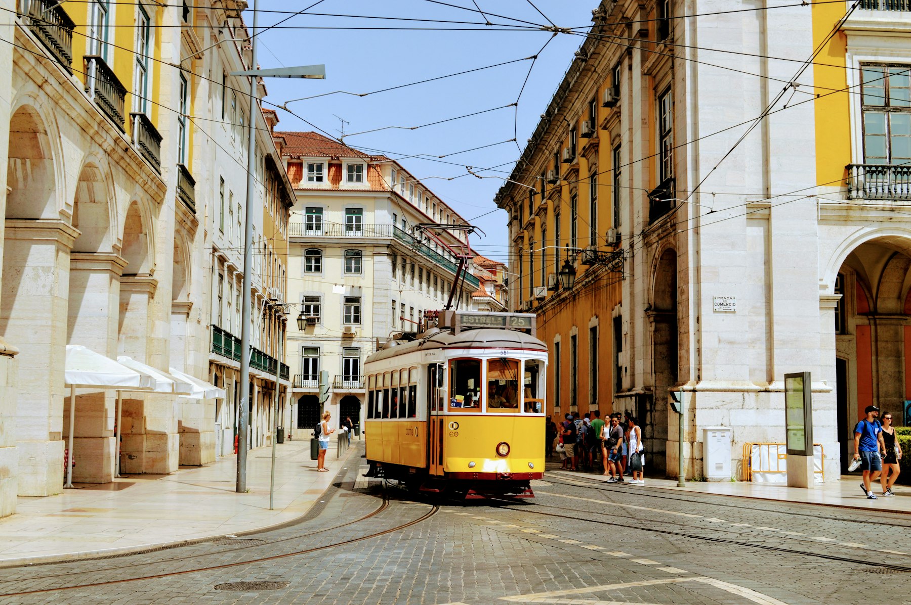 A yellow tram climbing a narrow street of historic buildings in Lisbon, the longest stop on this Spain and Portugal itinerary.