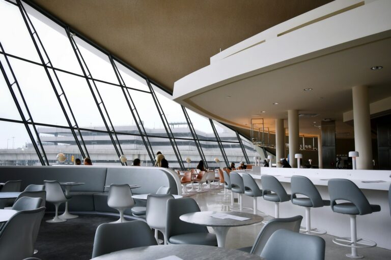Travellers seated on white chairs in an airport terminal lounge at New York JFK, the setting where a travel rewards credit card finally pays out
