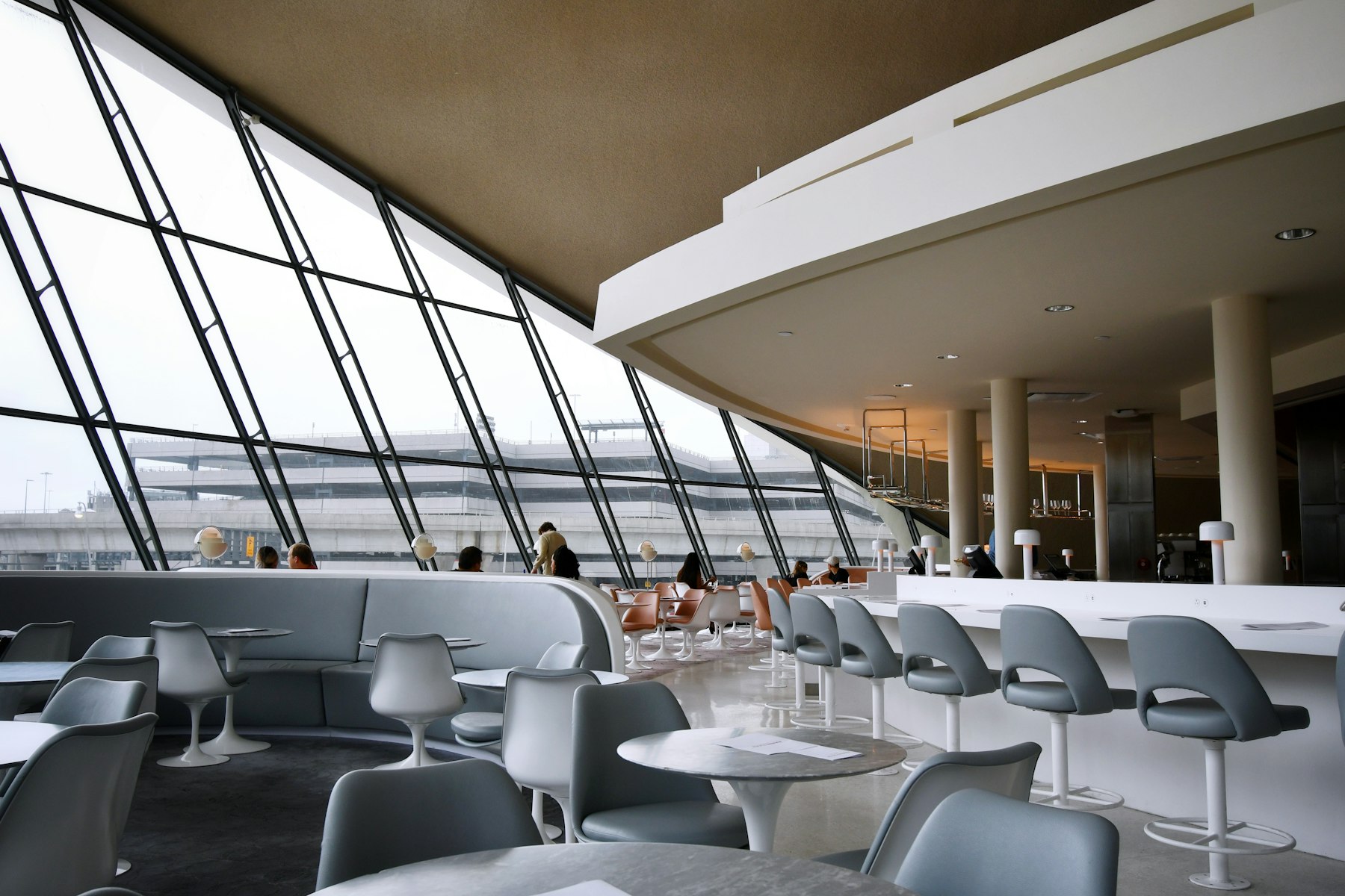 Travellers seated on white chairs in an airport terminal lounge at New York JFK, the setting where a travel rewards credit card finally pays out