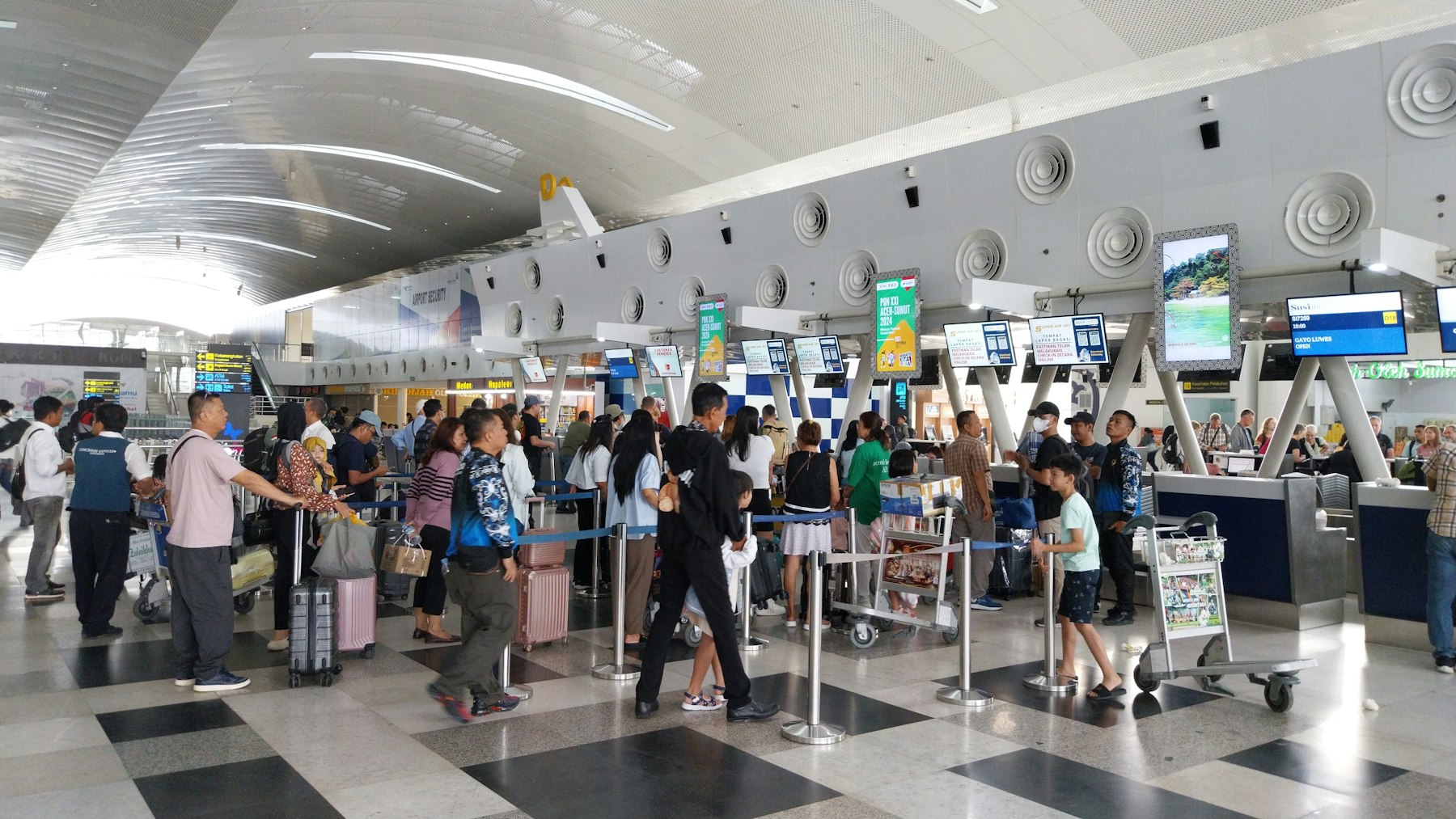 Airline Elite Status: Three Programs Just Moved the Bar 4 Travelers queuing with luggage at a busy airport check-in hall, the wait that airline elite status is mostly bought to avoid