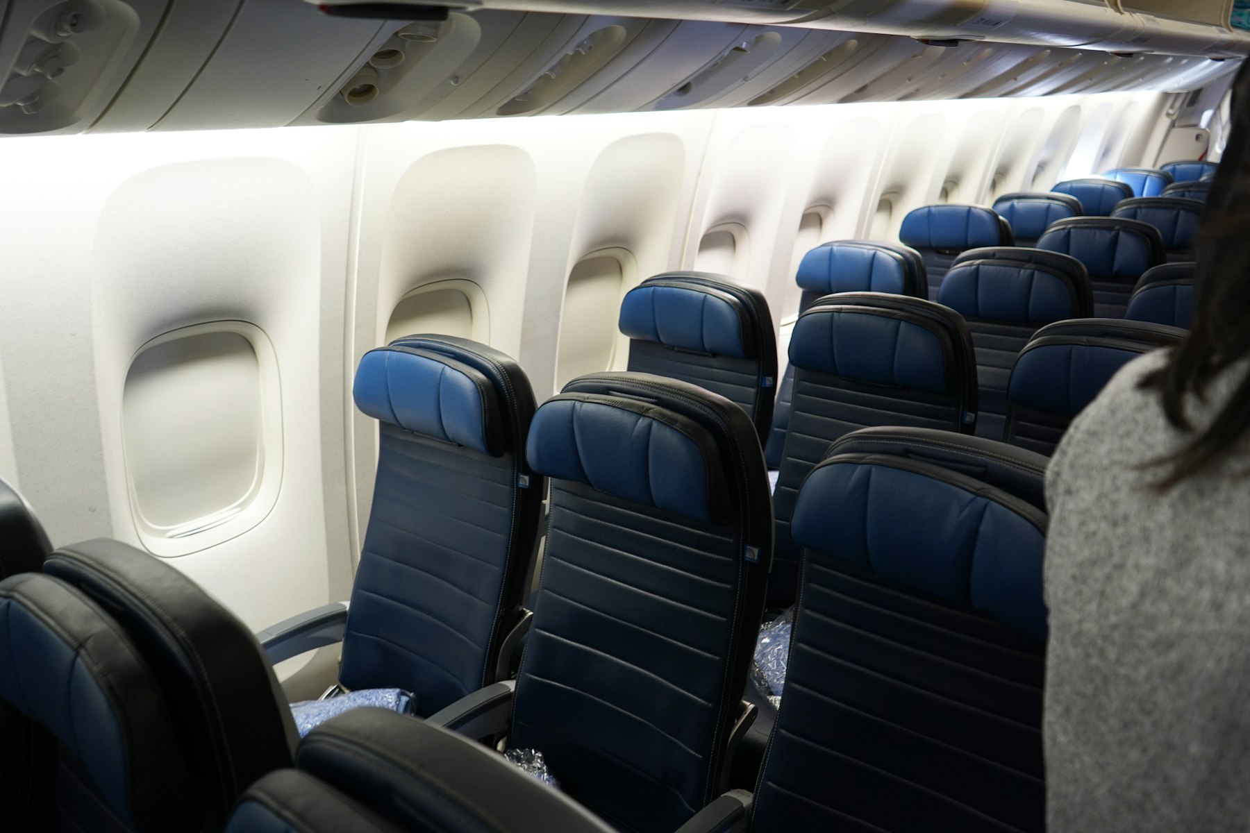 Airline Elite Status: Three Programs Just Moved the Bar 3 Rows of navy leather economy seats in a narrowbody cabin during boarding, the cabin most airline elite status is earned in