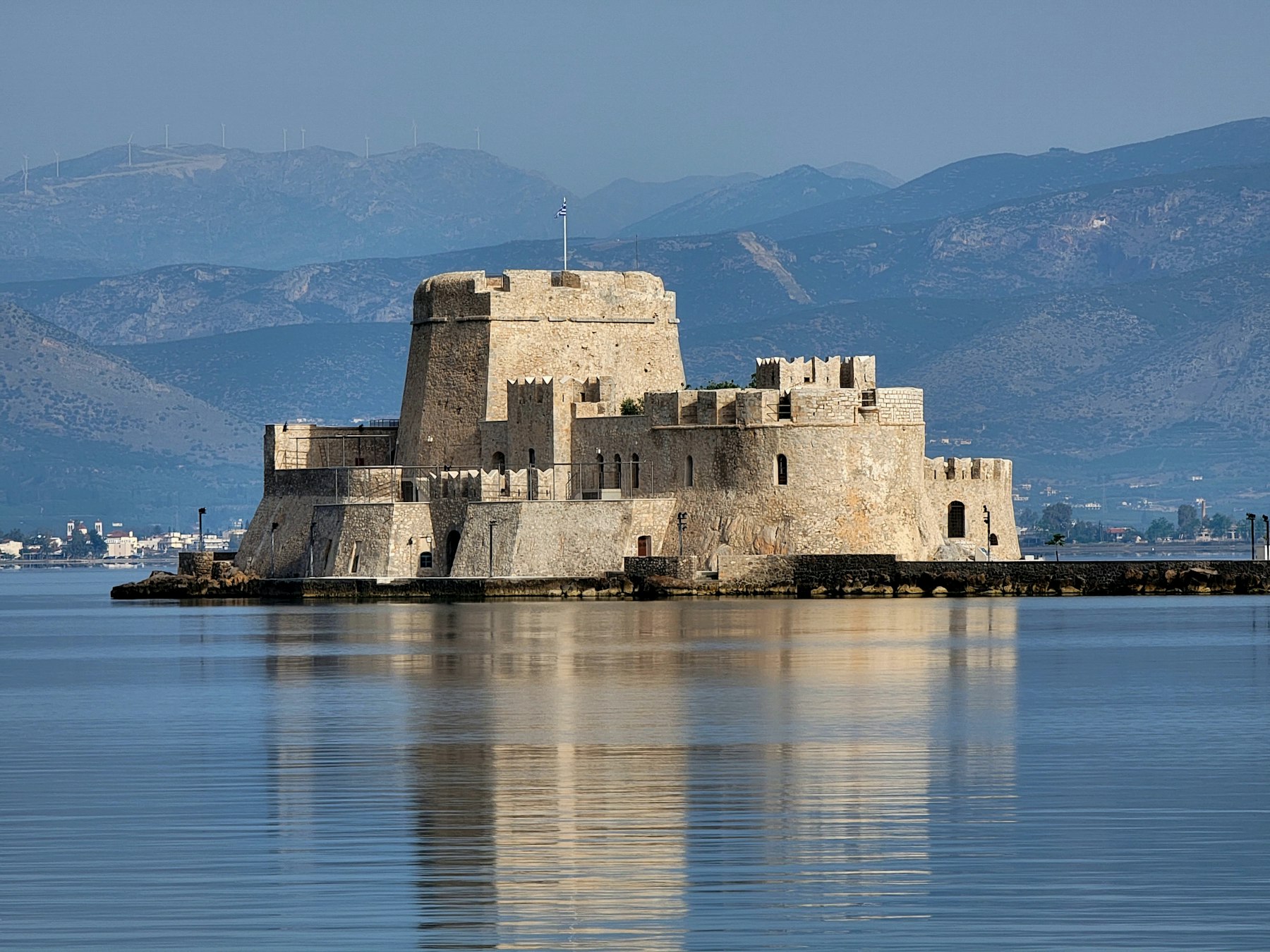 Best Tourist Cities in Greece: Start in Thessaloniki, Not Athens 3 The Bourtzi fortress standing in Nafplio harbour with the mountains of the Argolid behind it.