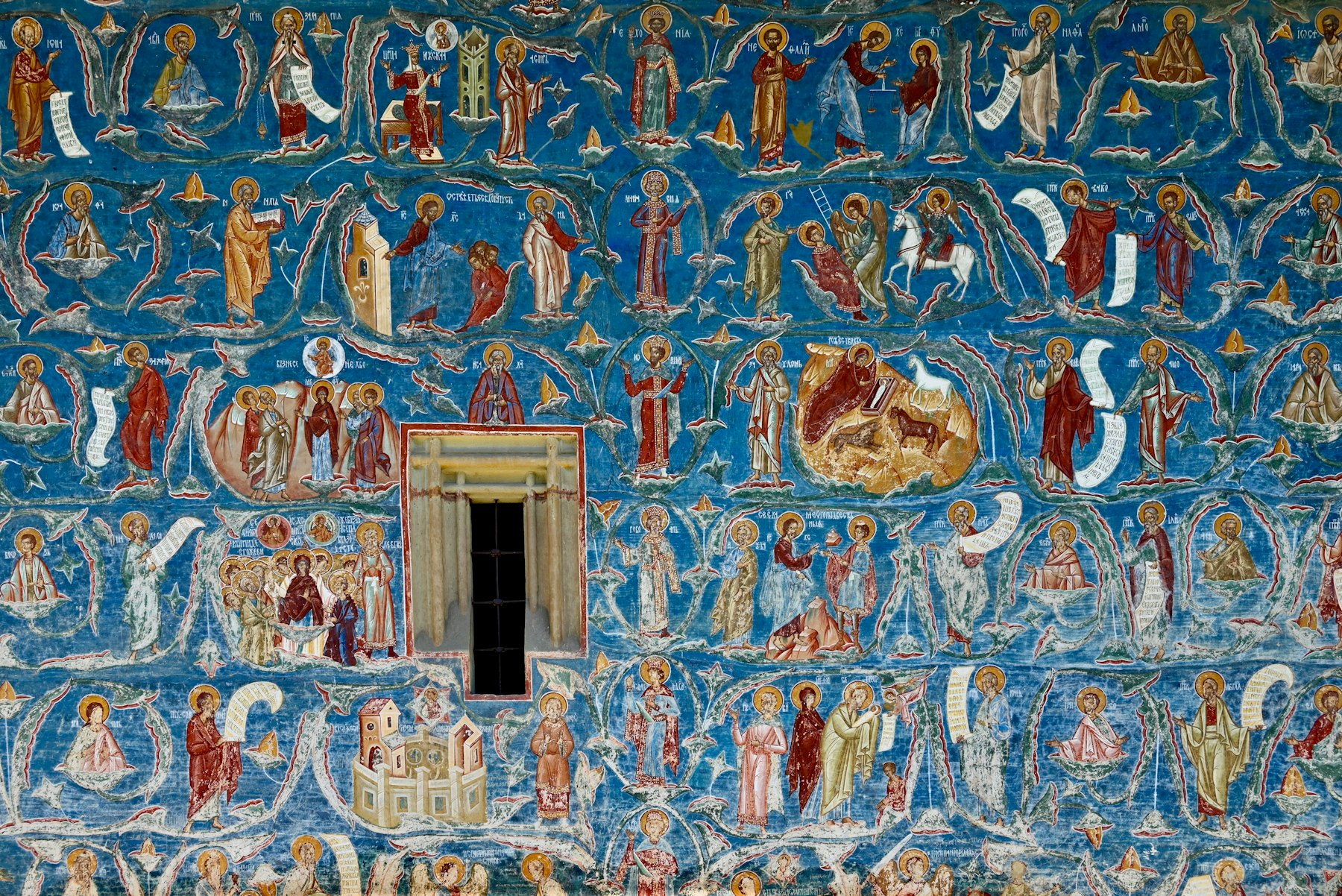 The blue exterior wall of Voronet monastery covered in painted figures, the final leg of this Romania itinerary