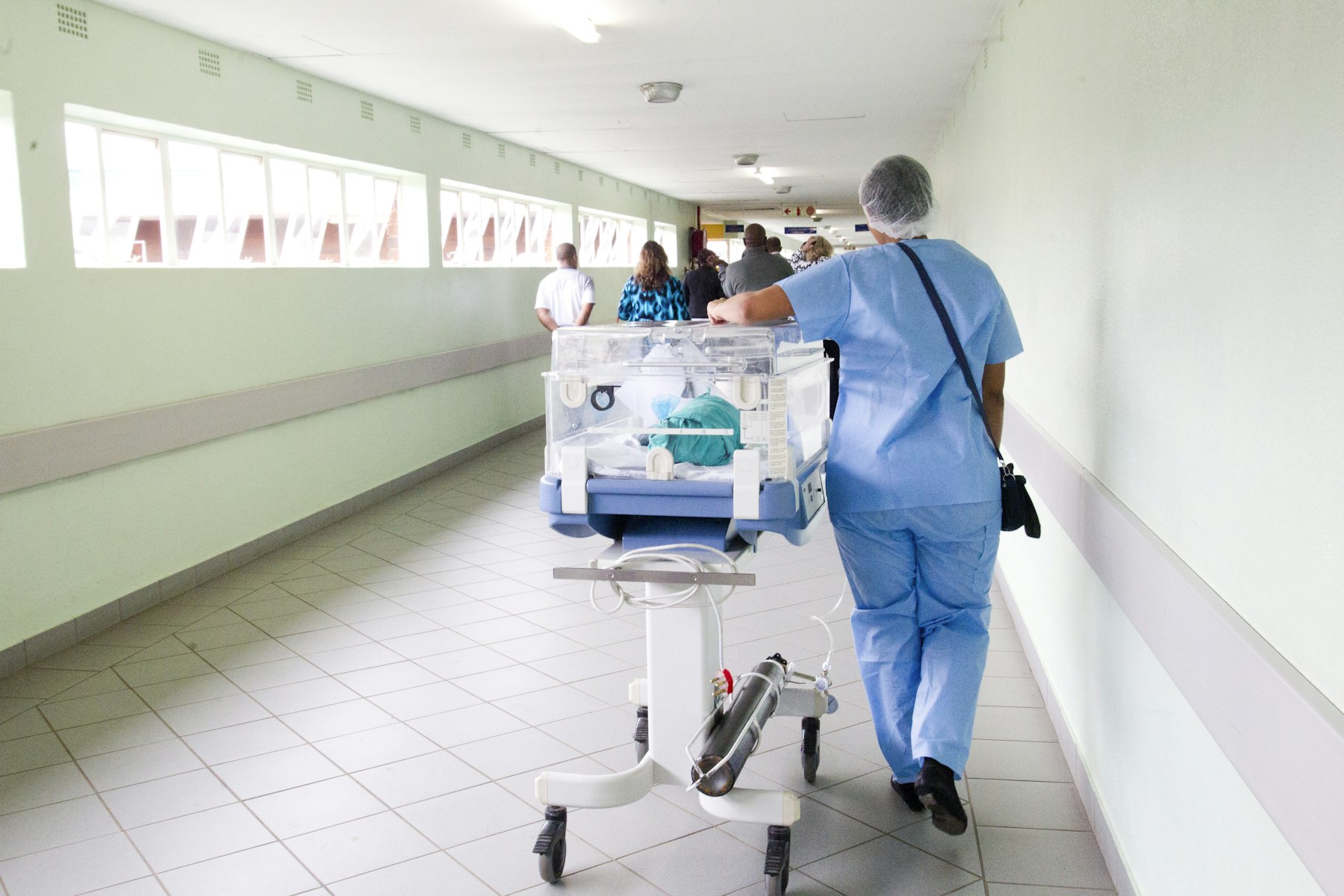 A nurse pushing an incubator along a hospital corridor in South Africa, the kind of facility travel insurance has to pay directly.