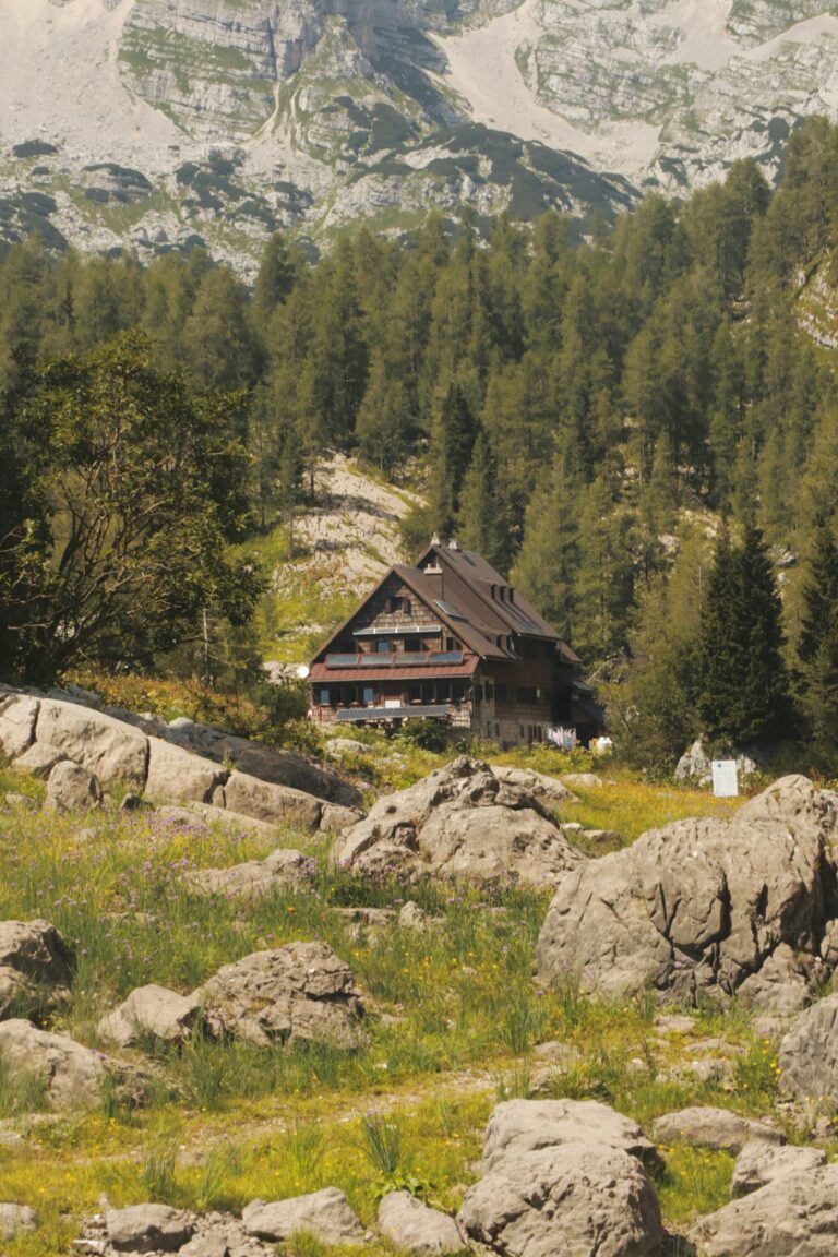 A timber mountain hut below a pale limestone cirque in the Julian Alps, the kind of bed that decides when trekking tours can actually run.