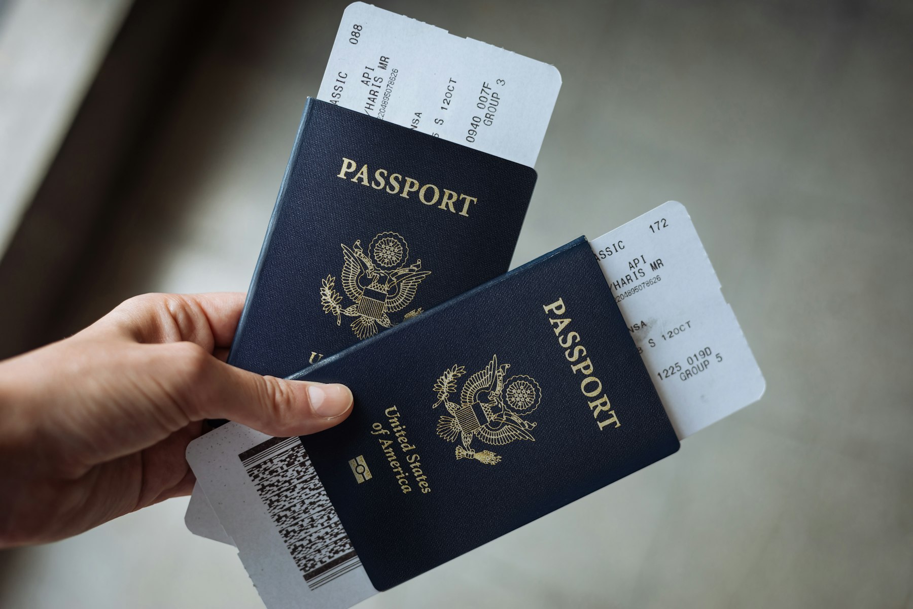 A hand holding two United States passports with boarding passes tucked inside, because the boarding pass is where TSA PreCheck benefits actually appear.